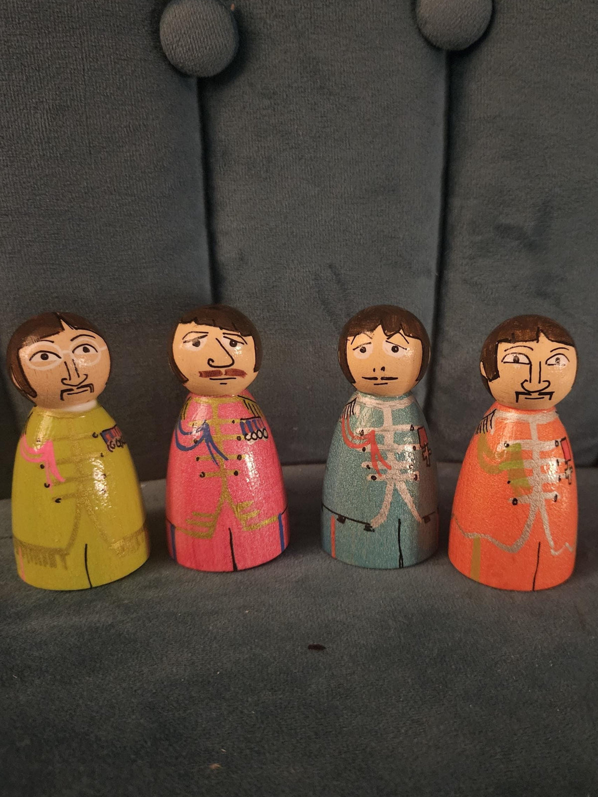 Four wooden figurines with colorful outfits on a dark textured surface