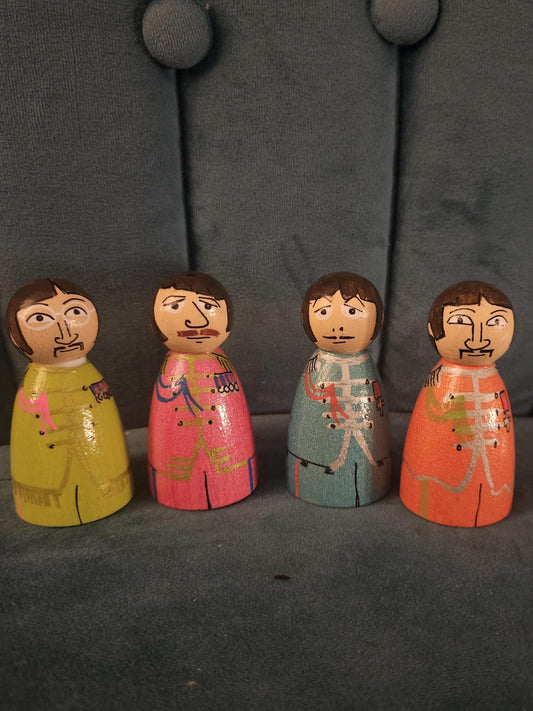 Four wooden figurines with colorful outfits on a dark textured surface