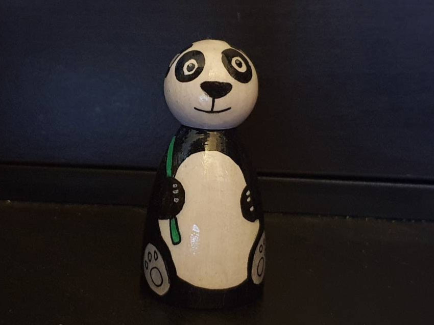 Panda-shaped figurine on a dark surface with a dark blue background