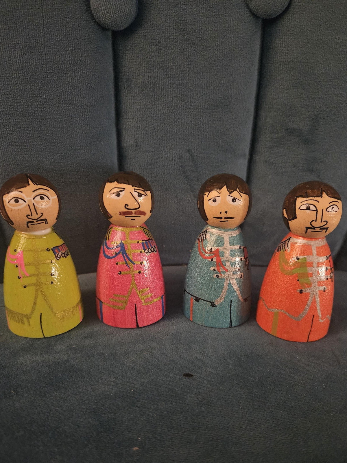 Four wooden figurines with colorful outfits on a gray surface